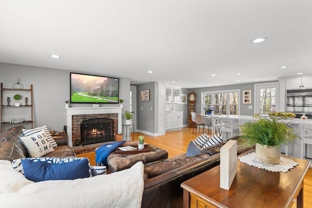 living area featuring baseboards, recessed lighting, light wood-style floors, and a fireplace