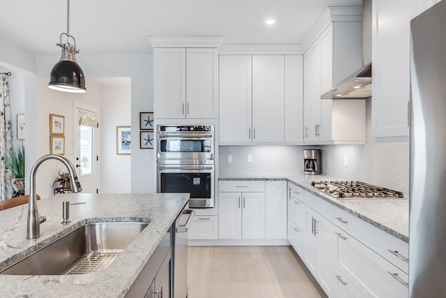 51 Tinkers Blf Unit 51, Plymouth, MA 02360 - kitchen featuring a sink, appliances with stainless steel finishes, decorative backsplash, wall chimney exhaust hood, and pendant lighting