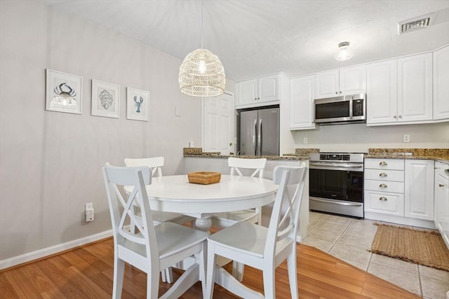 2 Englewood Dr Unit F-6, Harwich, MA 02645 - kitchen with appliances with stainless steel finishes, white cabinetry, dark stone countertops, hanging light fixtures, and light tile patterned flooring