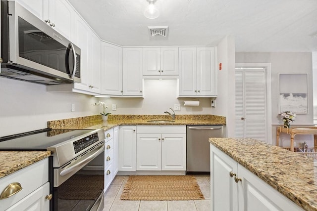 2 Englewood Dr Unit F-6, Harwich, MA 02645 - kitchen with stainless steel appliances, white cabinetry, light stone counters, and light tile patterned flooring
