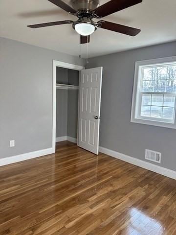 unfurnished bedroom featuring wood finished floors, baseboards, and visible vents