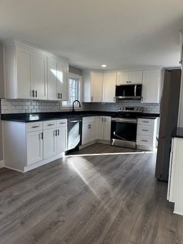 kitchen featuring dark countertops, white cabinets, appliances with stainless steel finishes, and dark wood finished floors