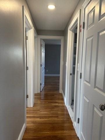 corridor with dark wood finished floors and baseboards