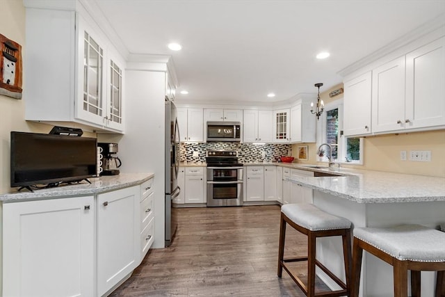22 Tenney St, Georgetown, MA 01388 - kitchen featuring appliances with stainless steel finishes, a breakfast bar area, a peninsula, dark wood-type flooring, and white cabinetry