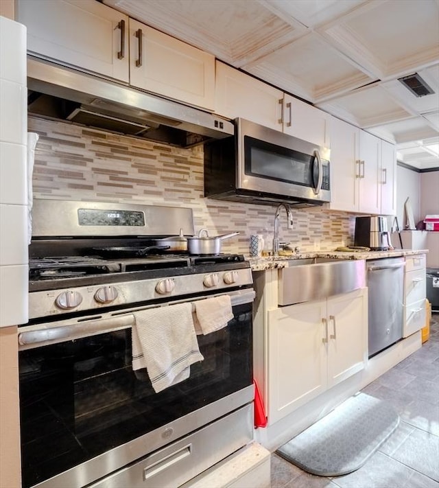 kitchen with light stone counters, white cabinets, backsplash, and appliances with stainless steel finishes