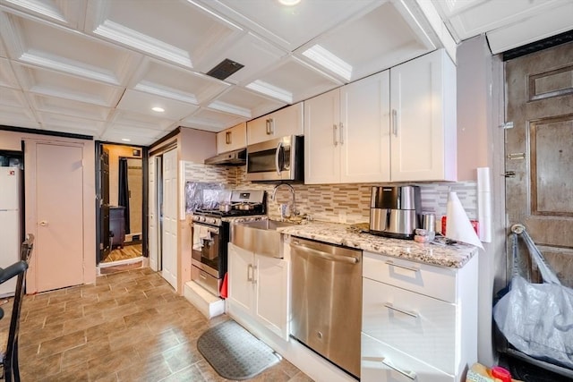 kitchen featuring appliances with stainless steel finishes, sink, white cabinetry, light stone counters, and decorative backsplash