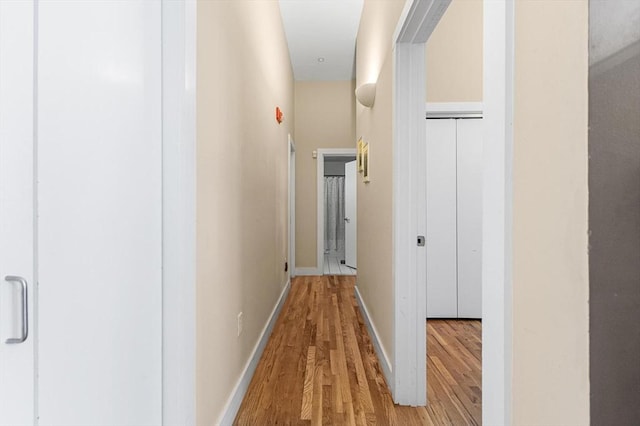 corridor with baseboards and light wood-style flooring