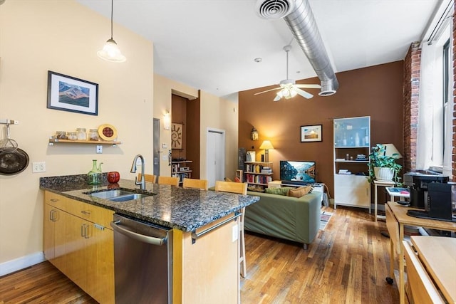 kitchen featuring ceiling fan, stainless steel dishwasher, wood finished floors, a sink, and a peninsula