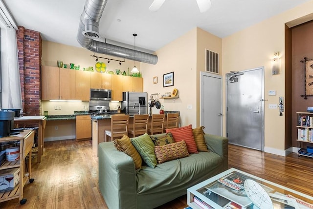 living room with ceiling fan, wood finished floors, and visible vents