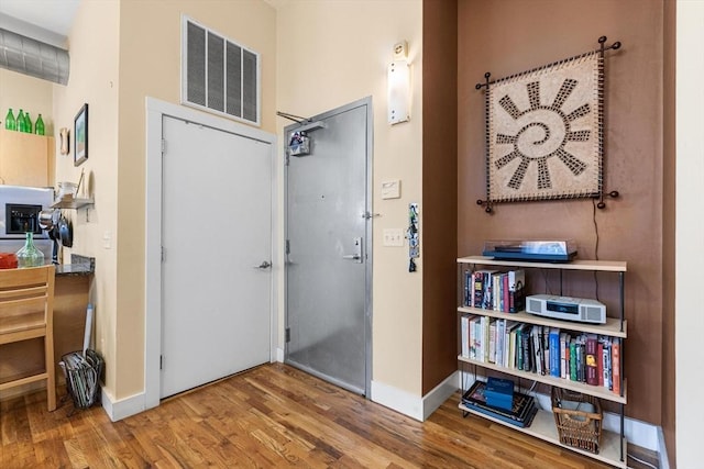 miscellaneous room with baseboards, wood finished floors, and visible vents