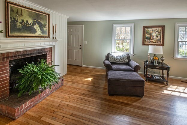 living room with a brick fireplace and hardwood / wood-style flooring