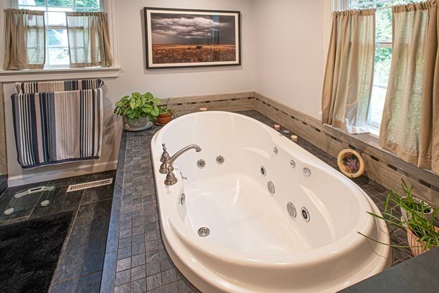 bathroom with tiled bath and a healthy amount of sunlight