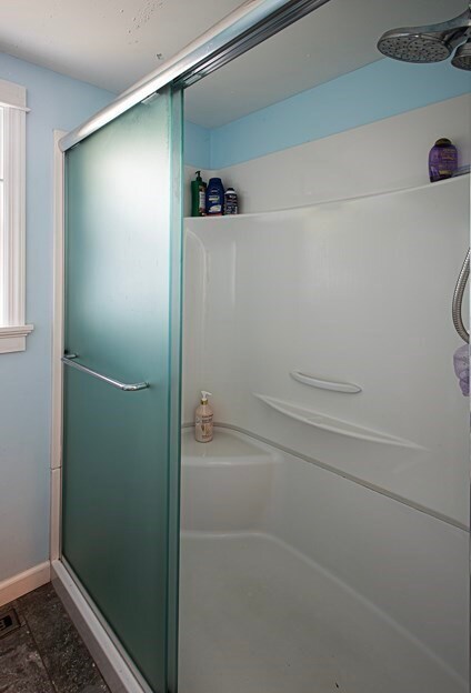 bathroom with walk in shower and ceiling fan