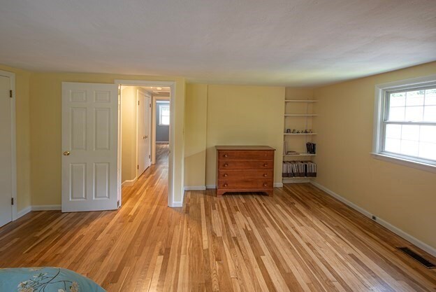 empty room with built in shelves, radiator, and light hardwood / wood-style flooring