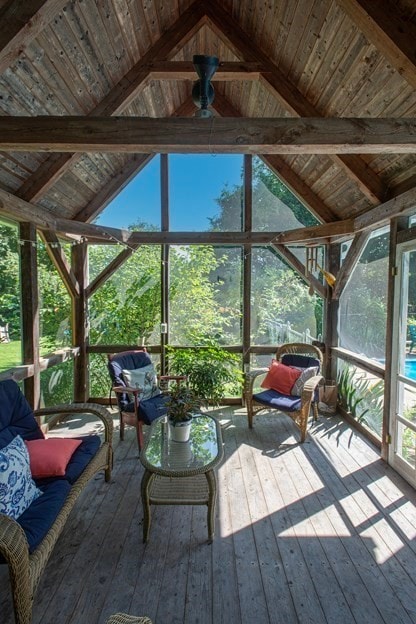 sunroom / solarium featuring ceiling fan, vaulted ceiling with beams, and wooden ceiling