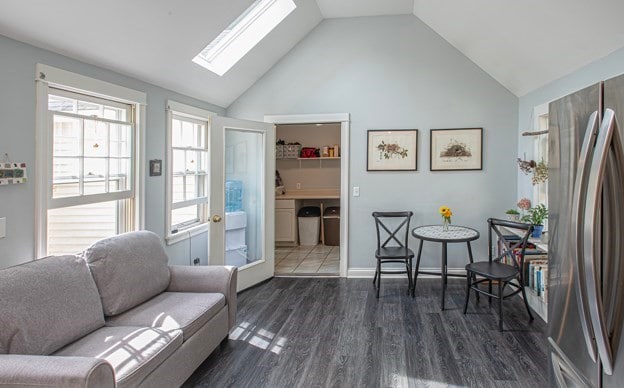 living room featuring dark hardwood / wood-style flooring, a skylight, and high vaulted ceiling