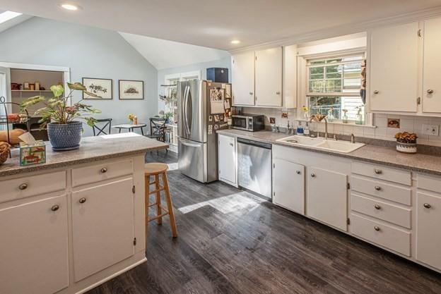 kitchen with appliances with stainless steel finishes, lofted ceiling, and white cabinetry