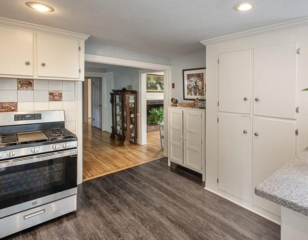 kitchen featuring white cabinets, dark wood-type flooring, stainless steel range with gas cooktop, and tasteful backsplash