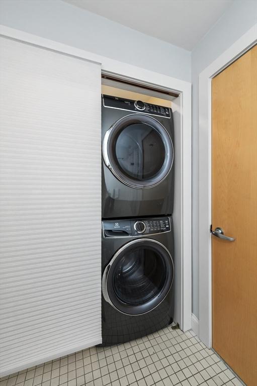 laundry room featuring stacked washer / dryer and light tile patterned floors