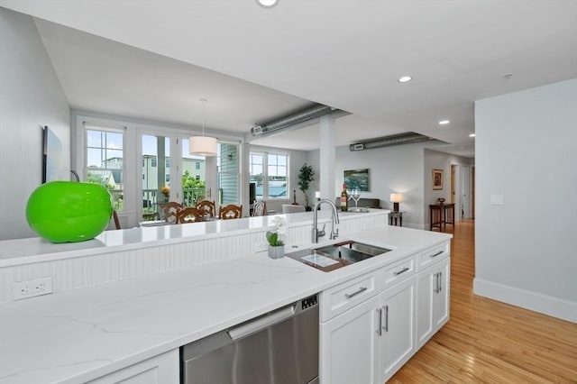 kitchen with sink, hanging light fixtures, light stone counters, white cabinets, and stainless steel dishwasher