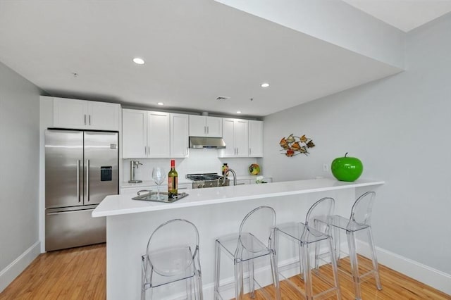 kitchen featuring decorative backsplash, high quality fridge, white cabinets, and kitchen peninsula