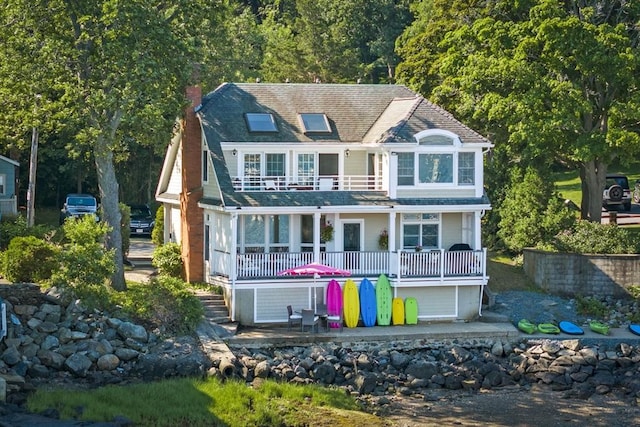 back of property with a balcony, a chimney, and a patio