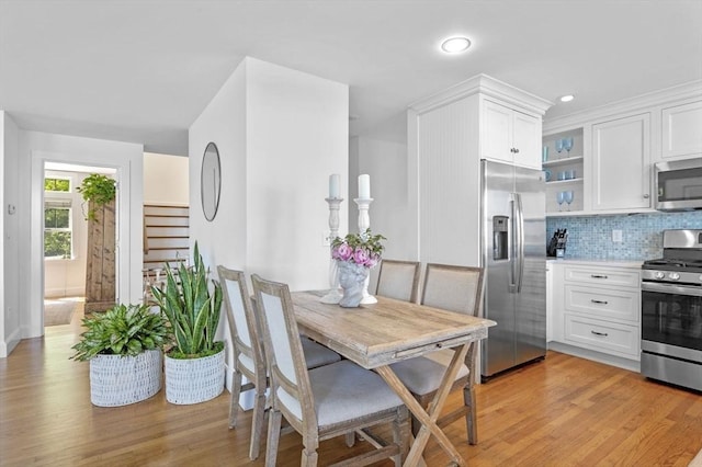 kitchen with appliances with stainless steel finishes, white cabinetry, backsplash, light wood-type flooring, and recessed lighting