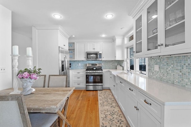 kitchen with stainless steel appliances, a sink, light wood-type flooring, light countertops, and recessed lighting