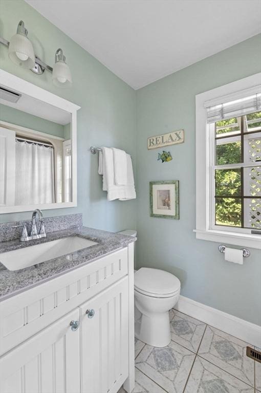 bathroom featuring toilet, baseboards, and vanity