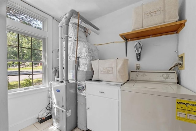 washroom with healthy amount of natural light, washer hookup, light tile patterned floors, and cabinet space