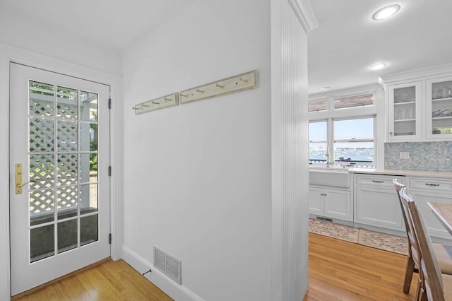 entryway featuring light wood-style floors, recessed lighting, a sink, and baseboards