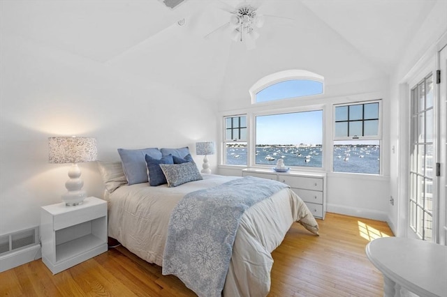 bedroom with light wood finished floors, vaulted ceiling, baseboards, and a ceiling fan