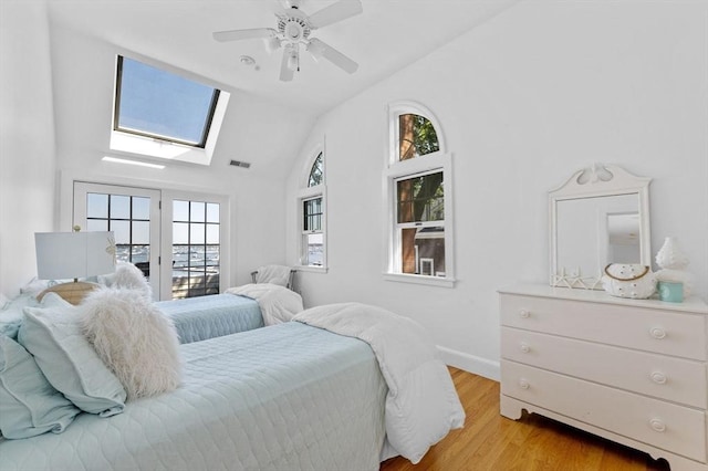 bedroom with light wood finished floors, a skylight, access to exterior, lofted ceiling, and baseboards