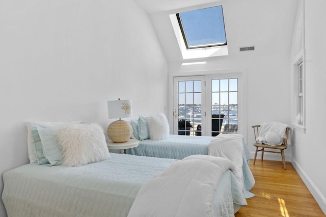 bedroom with a skylight, access to exterior, light wood-style flooring, high vaulted ceiling, and baseboards