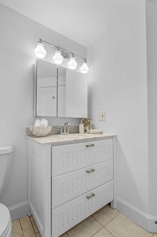 bathroom featuring toilet, tile patterned flooring, vanity, and baseboards