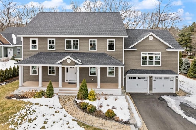 shingle-style home with a garage, driveway, a porch, and roof with shingles