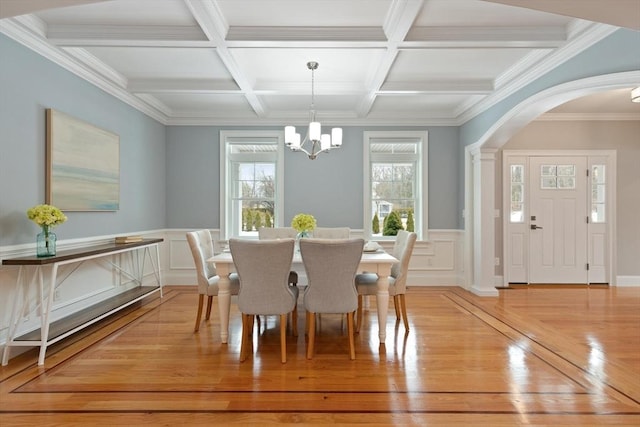 dining space featuring light wood-style floors, a healthy amount of sunlight, a notable chandelier, and beamed ceiling