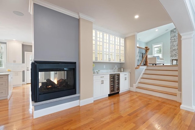 interior space featuring stairway, wine cooler, light wood-style flooring, and a dry bar