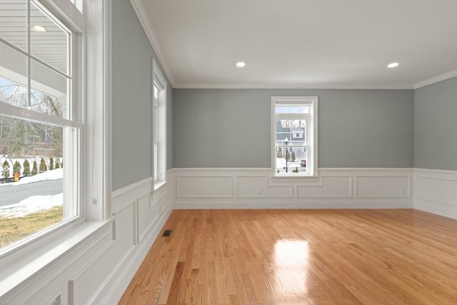 empty room featuring light wood finished floors, crown molding, and recessed lighting