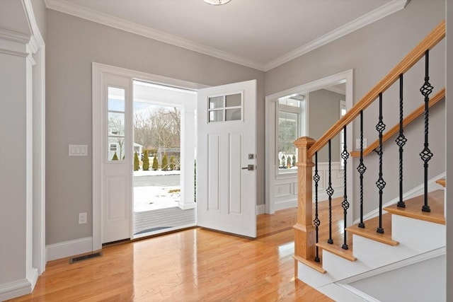 foyer entrance with visible vents, plenty of natural light, and wood finished floors