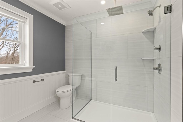 bathroom featuring a wainscoted wall, a stall shower, toilet, and crown molding