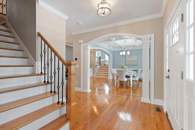 entryway featuring visible vents, arched walkways, coffered ceiling, light wood-style flooring, and stairway