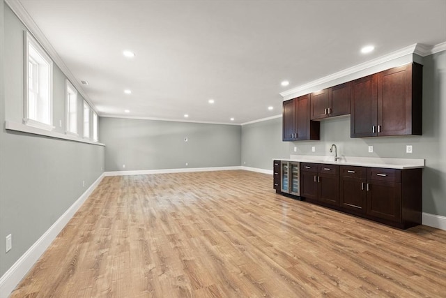 kitchen featuring beverage cooler, ornamental molding, light countertops, light wood-style floors, and a sink