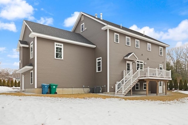 snow covered property with stairs, central AC unit, and a deck