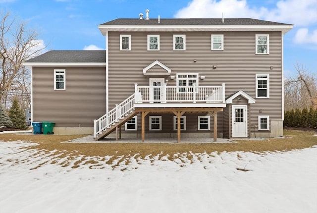 snow covered rear of property with stairs and a wooden deck