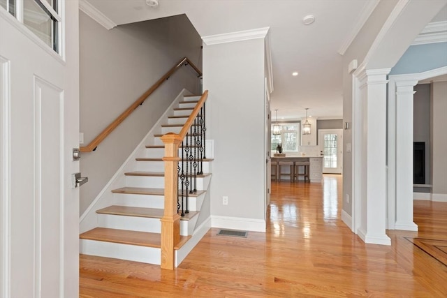 staircase featuring ornamental molding, visible vents, decorative columns, and wood finished floors