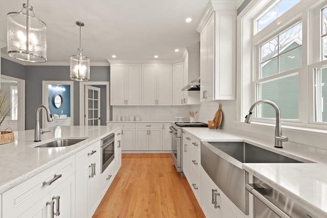 kitchen featuring white cabinetry, stainless steel appliances, a sink, and decorative light fixtures