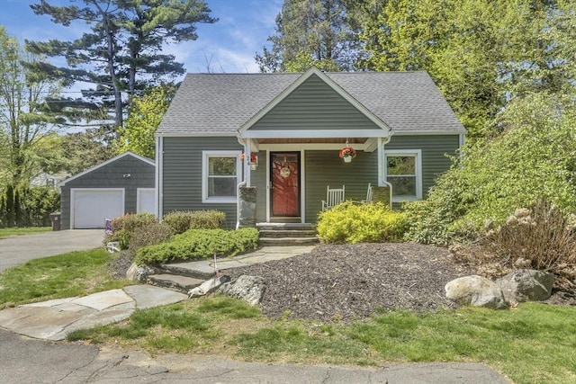 view of front of property with a detached garage, an outbuilding, and a shingled roof