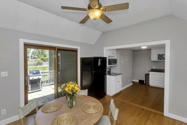 dining room with ceiling fan, vaulted ceiling, baseboards, and light wood finished floors
