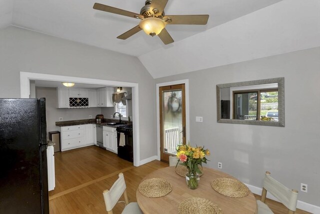 dining space with a ceiling fan, baseboards, vaulted ceiling, and wood finished floors